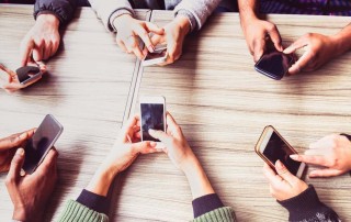 people hands using their mobile phones around a table