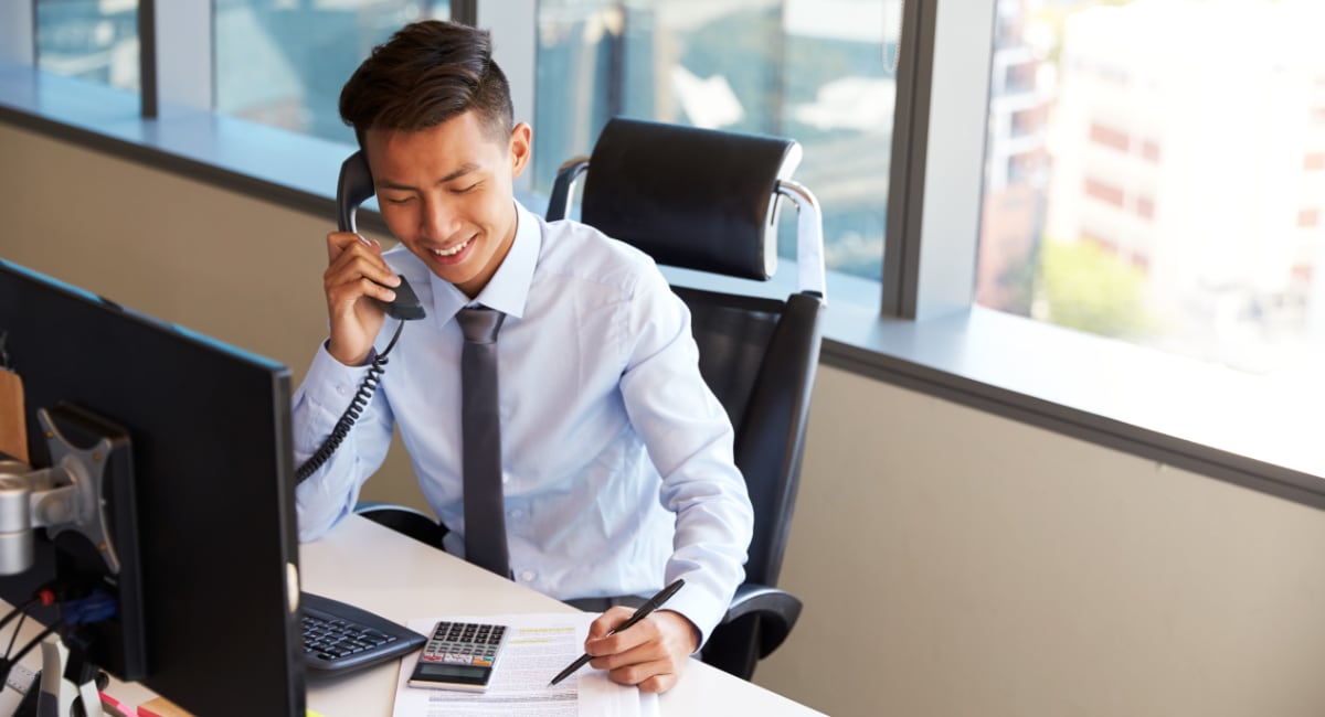 man on the phone calculating and taking notes