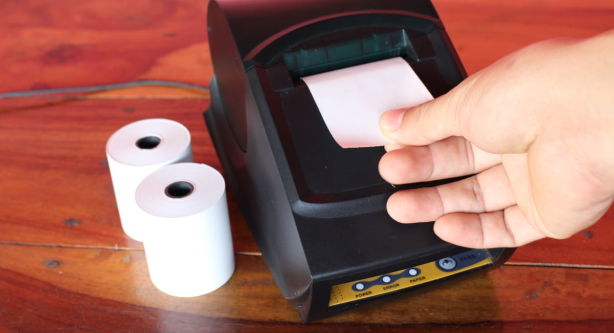 Receipt printer with paper rolls and hand ripping off receipt