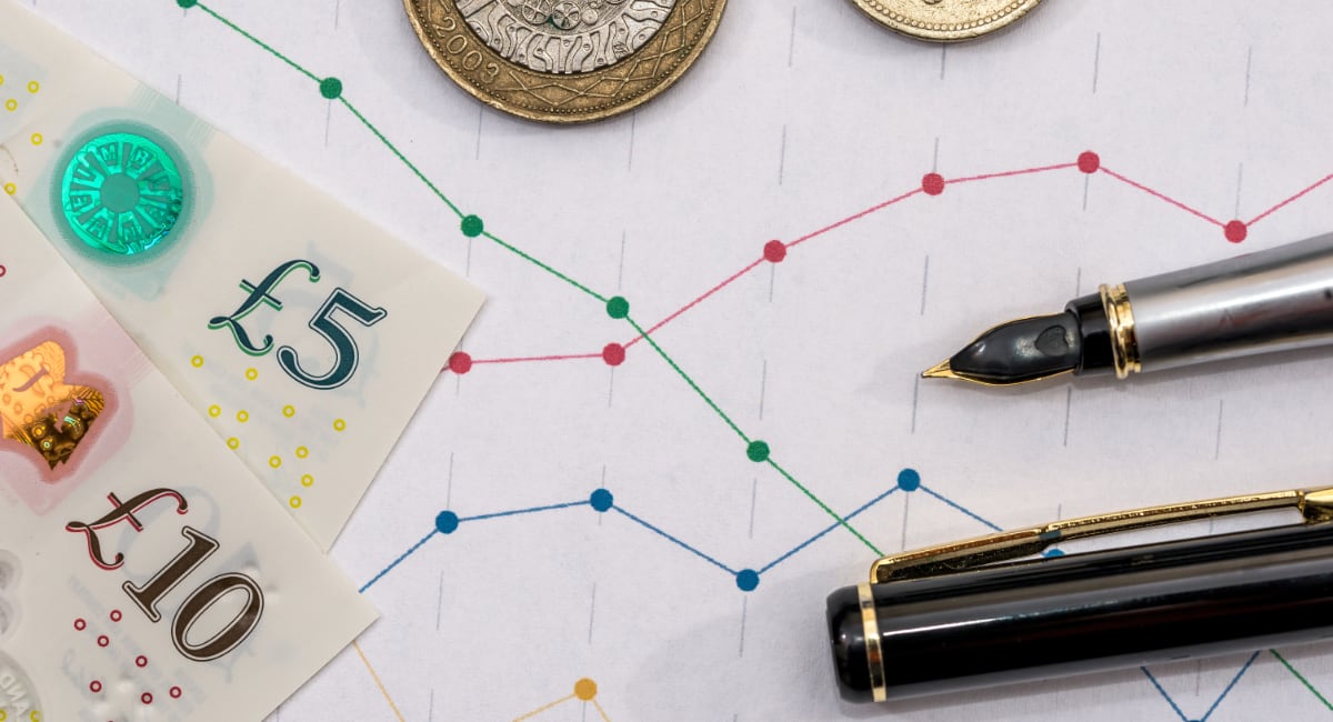 Pound notes and coins with sales figures and pens