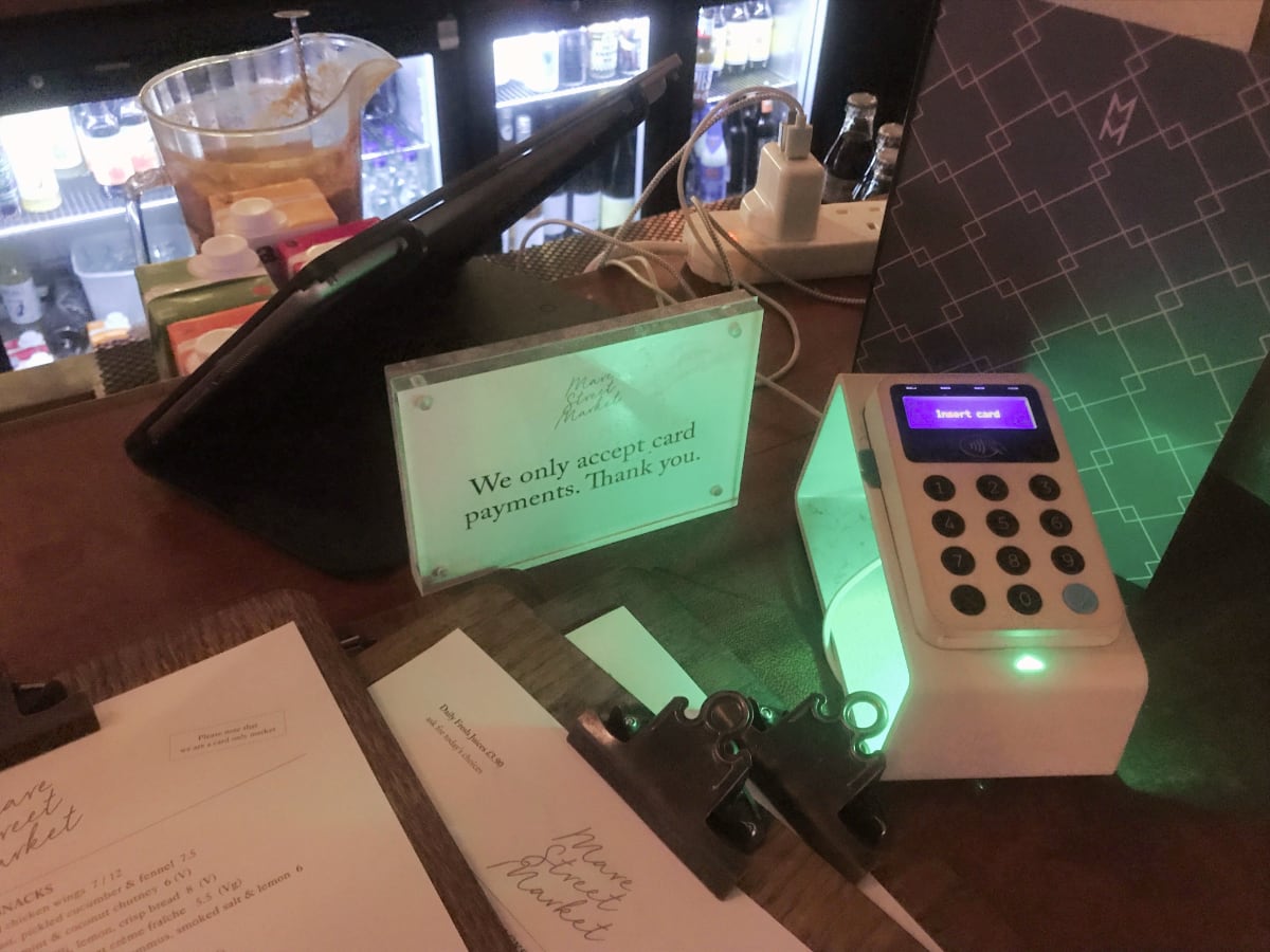 “We only accept card” signage in bar next to card reader We only accept cards sign next to a card reader