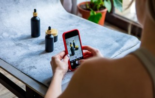 person taking iPhone photo of small bottles
