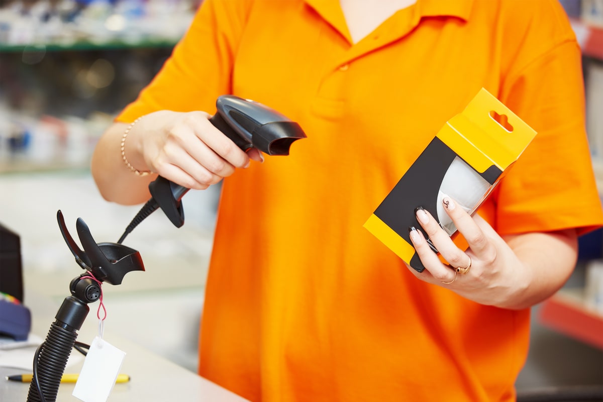 A handheld barcode scanner with a cable and holder retail worker scanning a product with a barcode scanner