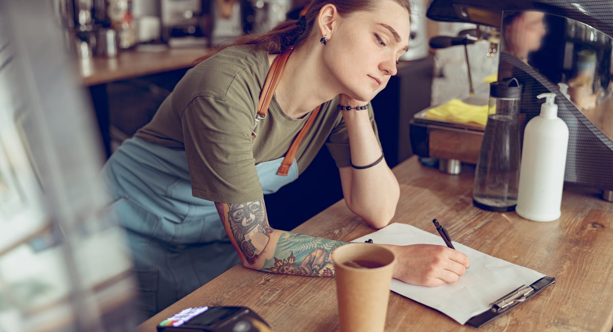 cafe worker writing VAT rates on paper