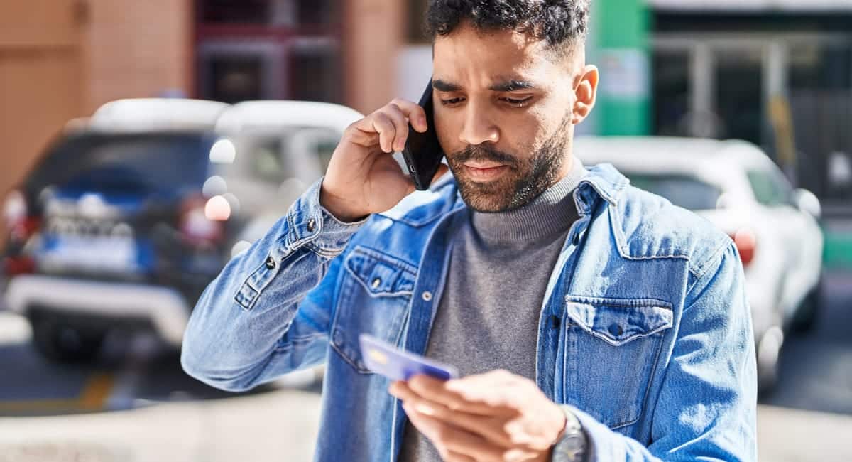 man on his phone while holding credit card